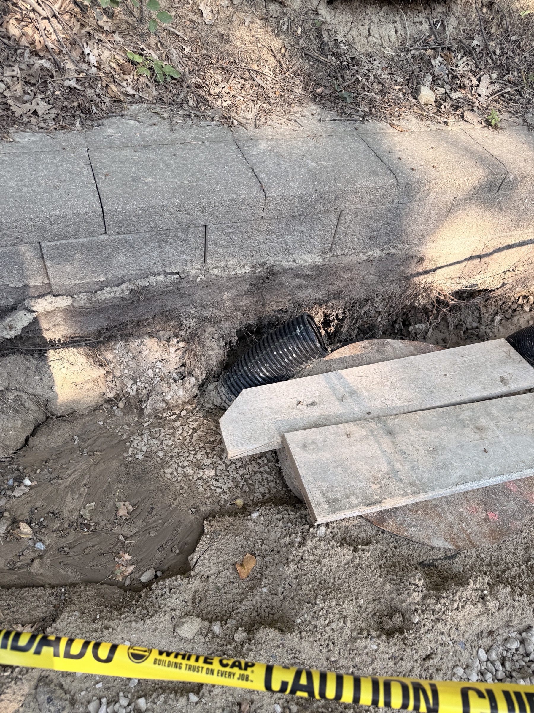 The trench beneath the retaining wall with drain pipe